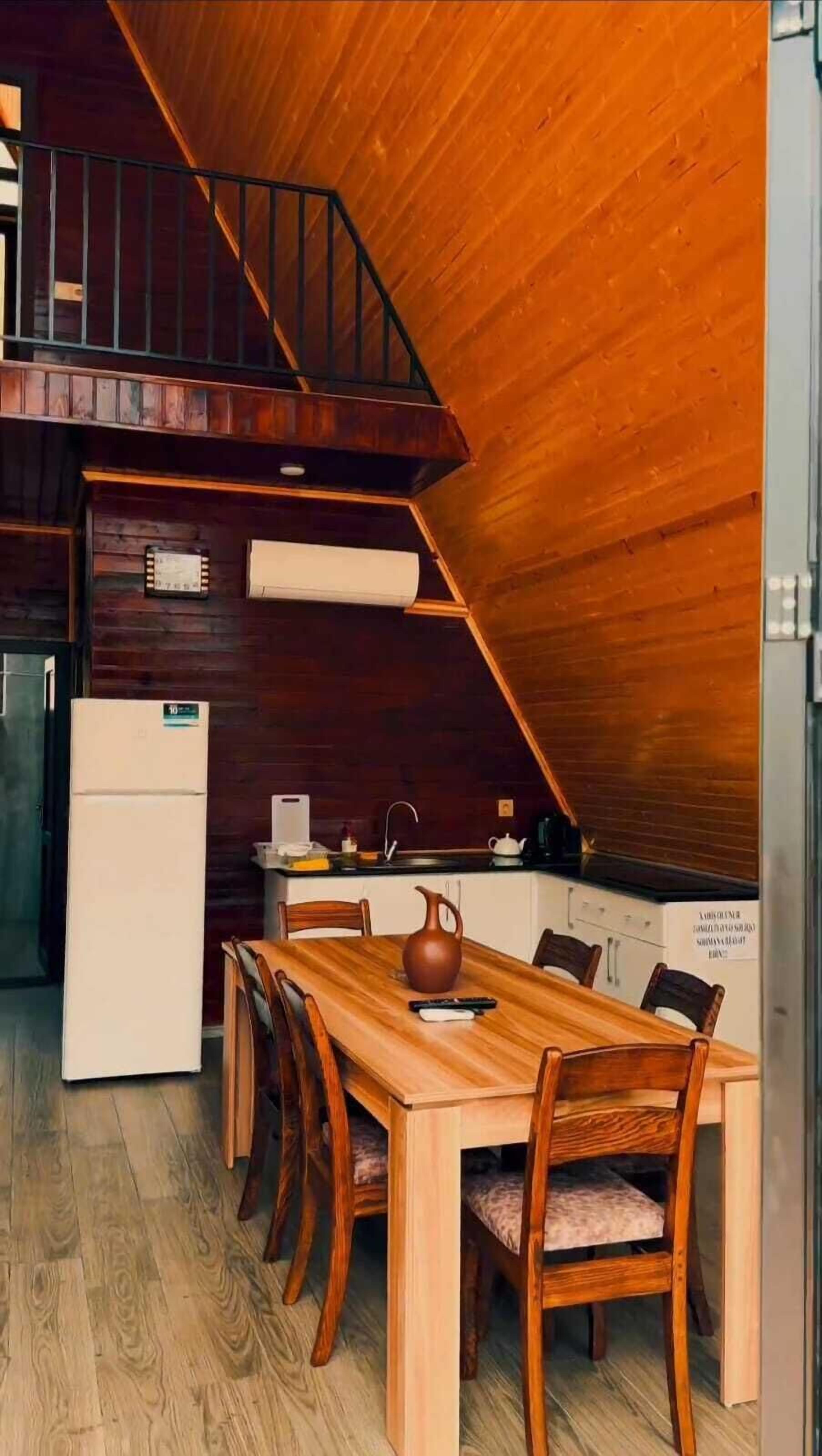 A compact kitchen with a wooden table and chairs, a refrigerator, and a sink.