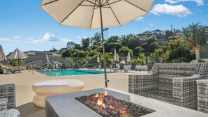 A poolside area with lounge chairs, a fire pit, and an umbrella. - Spring Special 15% Off a Luxury Townhome with Pool & A/C (Oceanside)