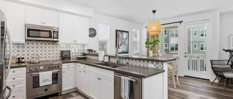 A modern kitchen with white cabinets, a stainless steel stove, and a large island with a sink.