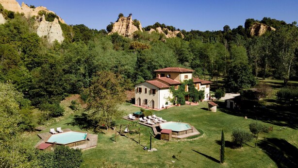 Una villa con piscina, cancha de tenis y jardín.