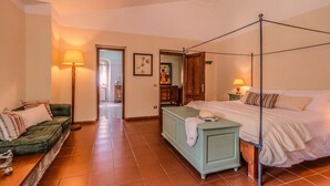 Un dormitorio con una cama con dosel, un sofá verde, un armario de madera y una lámpara.