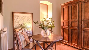 Un comedor con una mesa redonda de madera, sillas, un cojín a rayas, un jarrón decorativo y un mueble de madera grande.