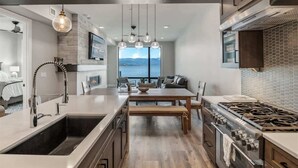 A modern kitchen with a central island, stainless steel appliances, and a view of the outdoors.