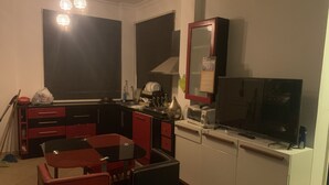 Une cuisine compacte comprenant une table et des chaises, un four à micro-ondes, une cuisinière et un grand téléviseur à écran plat.