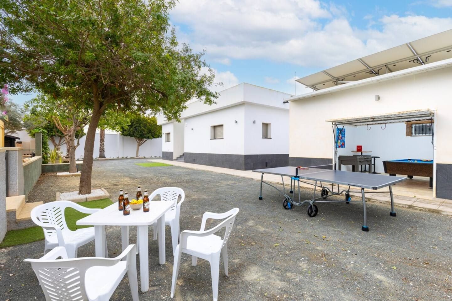 Ein Innenhof mit Tischtennisplatte, Stühlen und Bierflaschen.