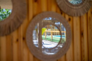 Ein rundes Fenster mit Blick auf eine Holzkonstruktion und eine Grünanlage.