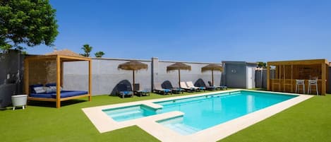 Une piscine avec des chaises longues et une pergola en bois.