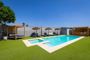 A swimming pool with lounge chairs and a wooden pergola.