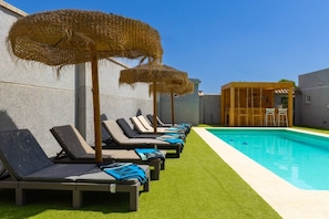 A poolside area with lounge chairs and a wooden structure with bar seating. - WaterWheel Villa by Fidalsa (Almoradí)