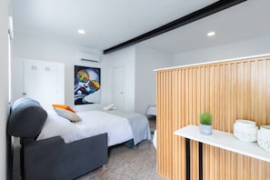 Ein modernes Hotelzimmer mit Bett, Schreibtisch, Zimmerpflanze und einem Gemälde an der Wand.