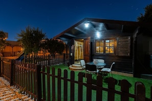 A wooden cabin with a fenced yard, a small patio with chairs, and a window with curtains. - WaterWheel Villa by Fidalsa (Almoradí)