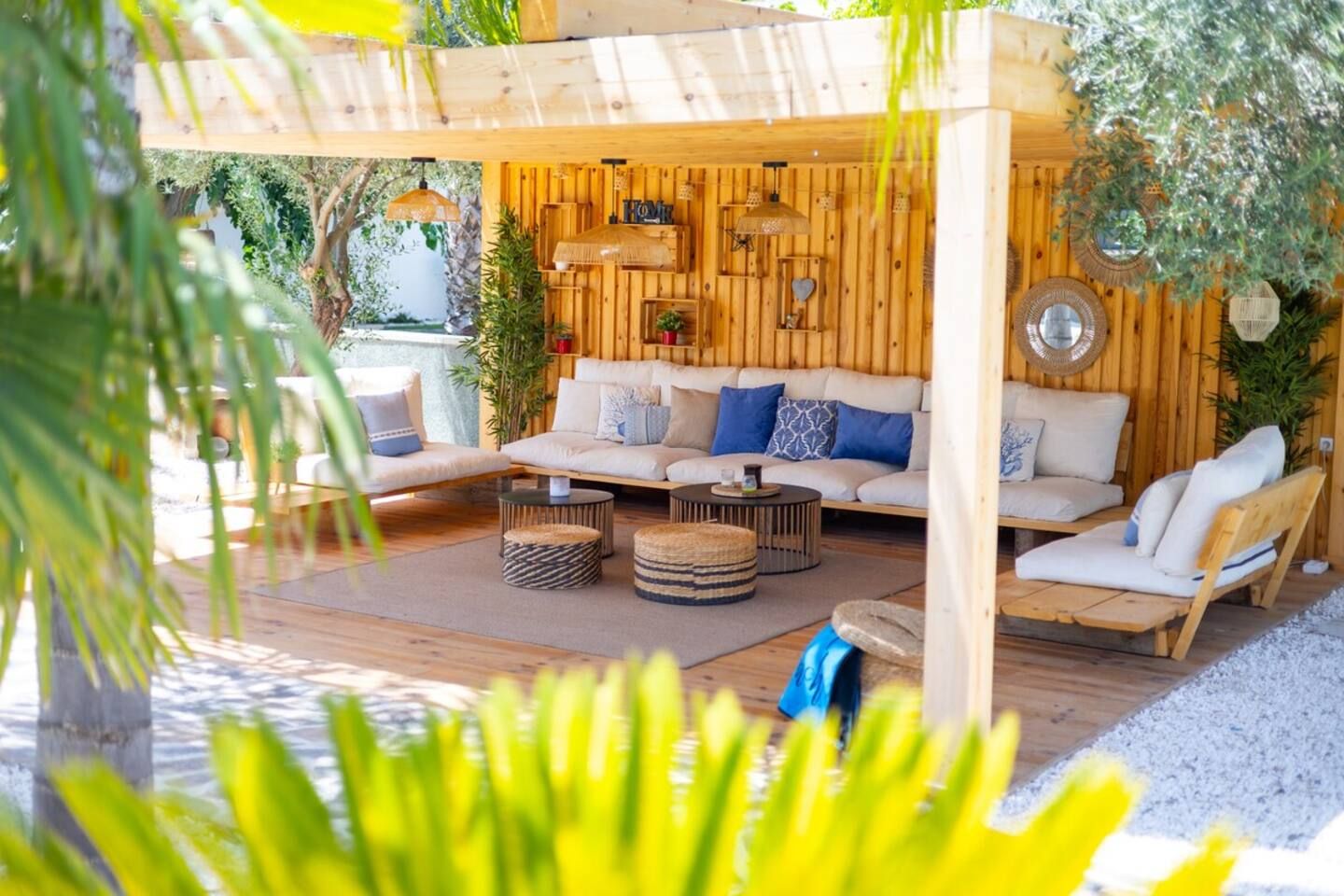Un área de estar al aire libre con un pérgola de madera, un conjunto de sofá y una mesa redonda de centro.