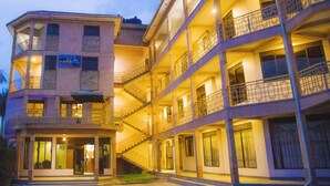A multi-story hotel with balconies, a cafe, and a well-lit entrance. - UBUNTU PALANCE HOTEL BY RUNATI (Kampala)