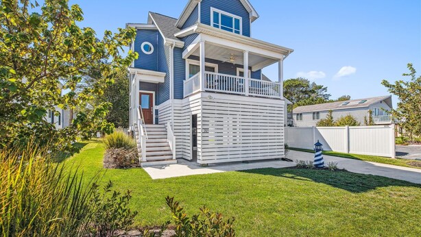 A two-story house with a blue and white exterior, a front porch, and a small front yard. - Bayside Bliss 205, Newly Constructed single family house in Uptown Ocean City (Ocean City)