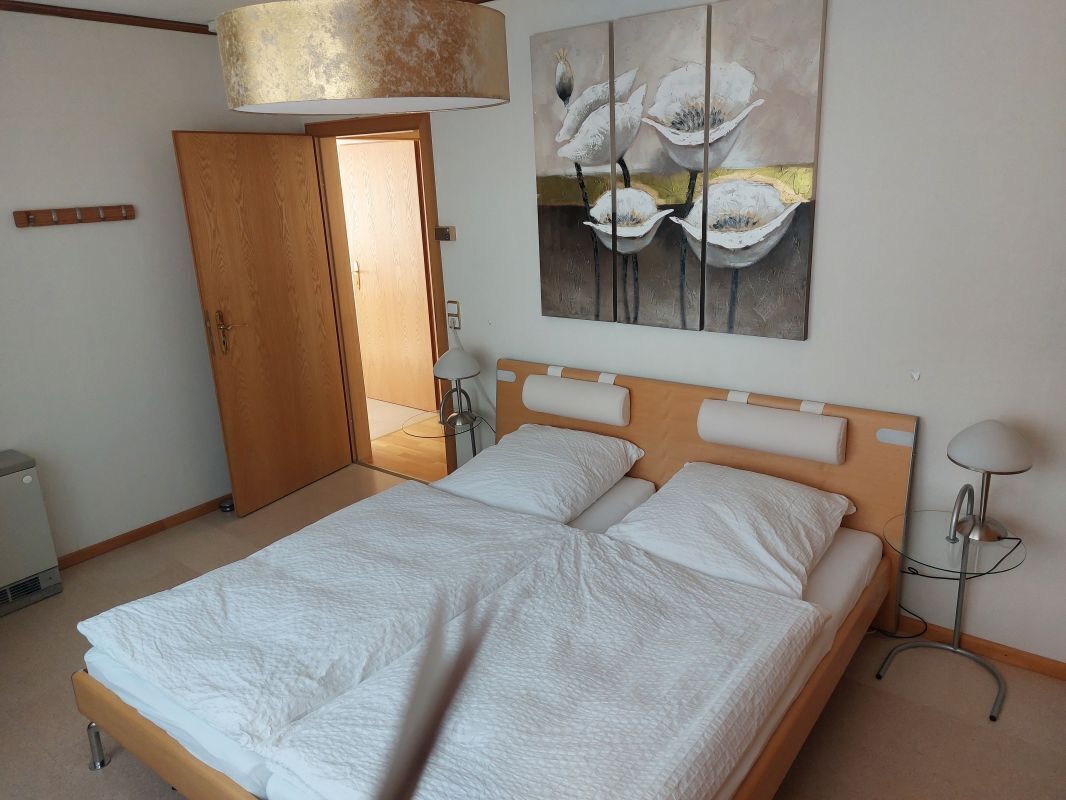 Una camera da letto con un letto, un armadio in legno, un quadro e una lampada da terra.