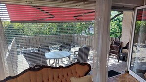 Ein Zimmer mit gepolsterten Sitzmöglichkeiten, einem Esstisch und Stühlen vor einer Glastür.