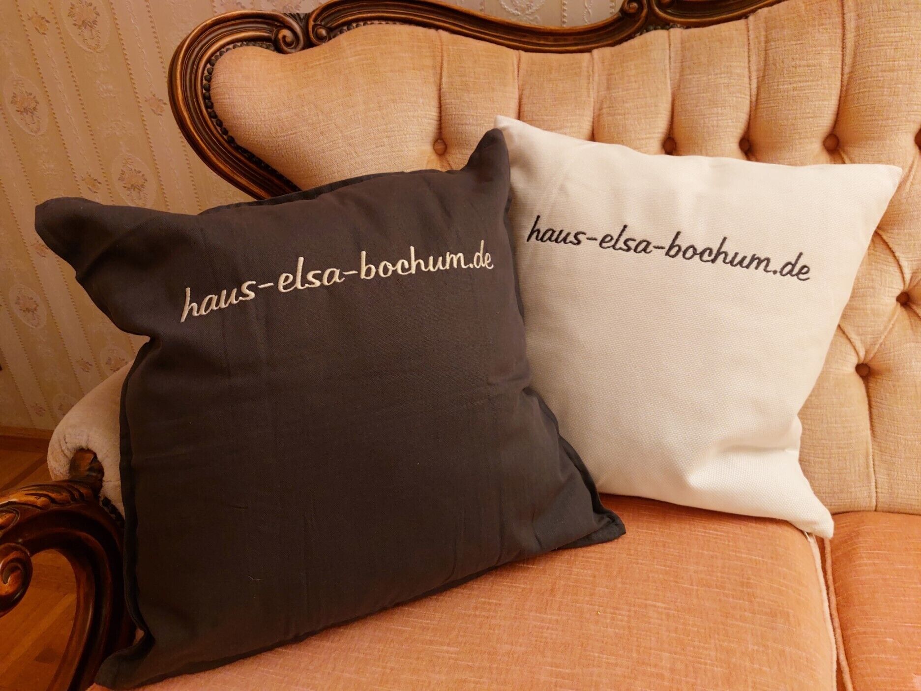 Zwei Kissen mit Aufdruck liegen auf einem Stuhl.