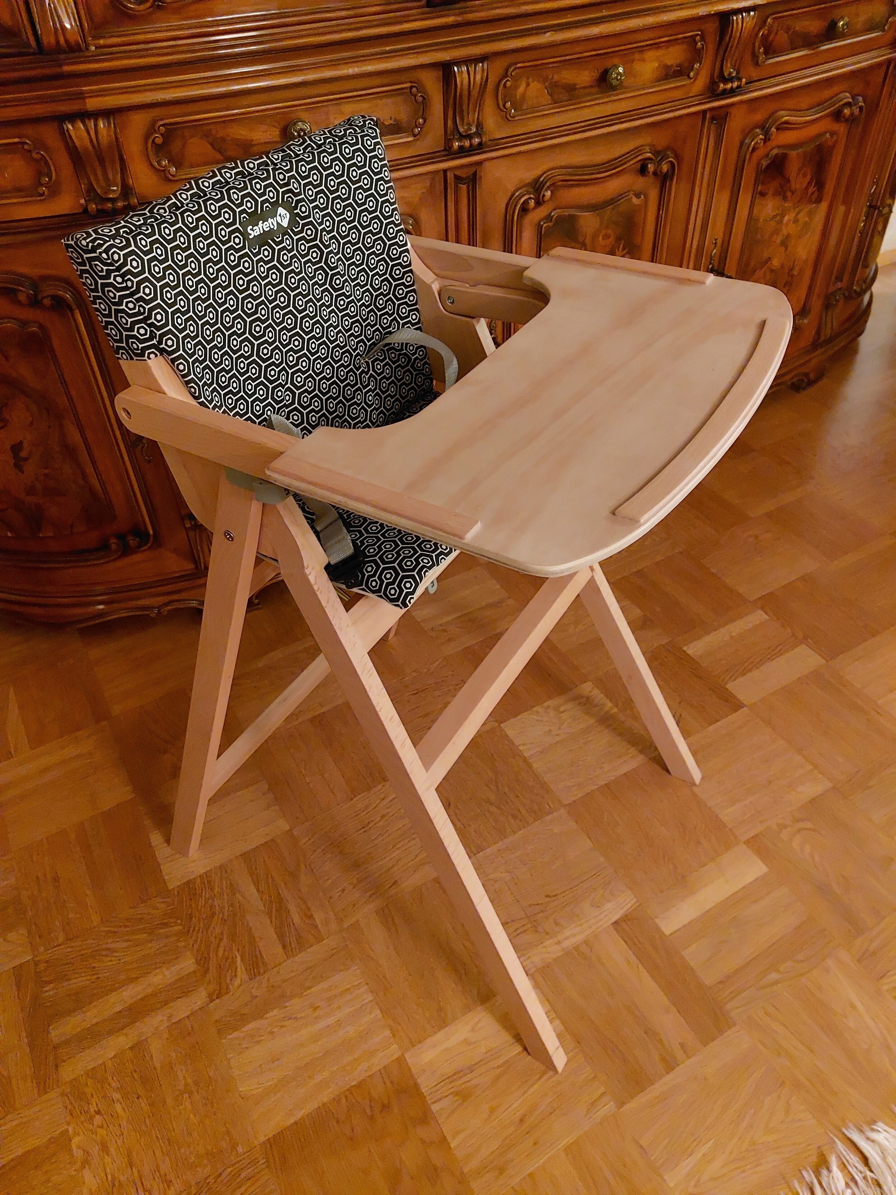 Une chaise en bois avec un coussin à motifs et un plateau de couleur claire.