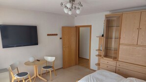 Ein Schlafzimmer mit einem Bett, einem Fernseher, einem Schreibtisch mit Stühlen und einem Kleiderschrank.
