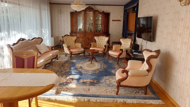 Ein traditionelles Wohnzimmer mit einem großen Holzschrank, einem Fernseher und einem gemusterten Teppich.