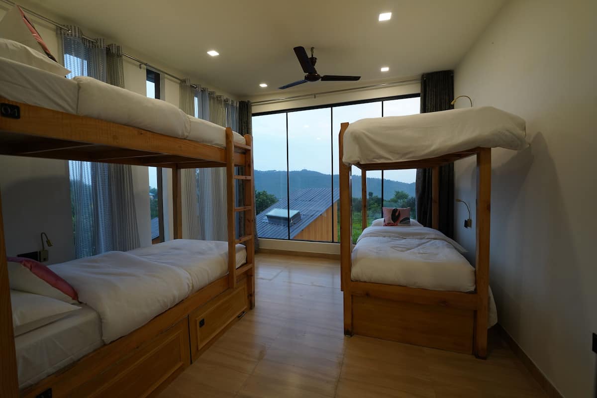 Una habitación con dos literas, un ventilador de techo y un ventanal con vistas al exterior.