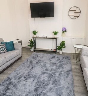Relax in this stylish living room with a flat-screen TV, comfortable sofa, and cozy rug.