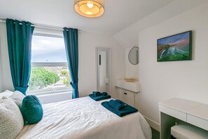 Relax in this inviting room with a comfortable bed, bedside table, and wall-mounted shelf, offering a peaceful view of the surrounding greenery.