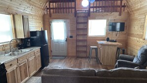 A cozy cabin interior with a kitchen, dining area, and a sofa. - Tan cabin close to University of Central Missouri and Whiteman AF Base  (Warrensburg)
