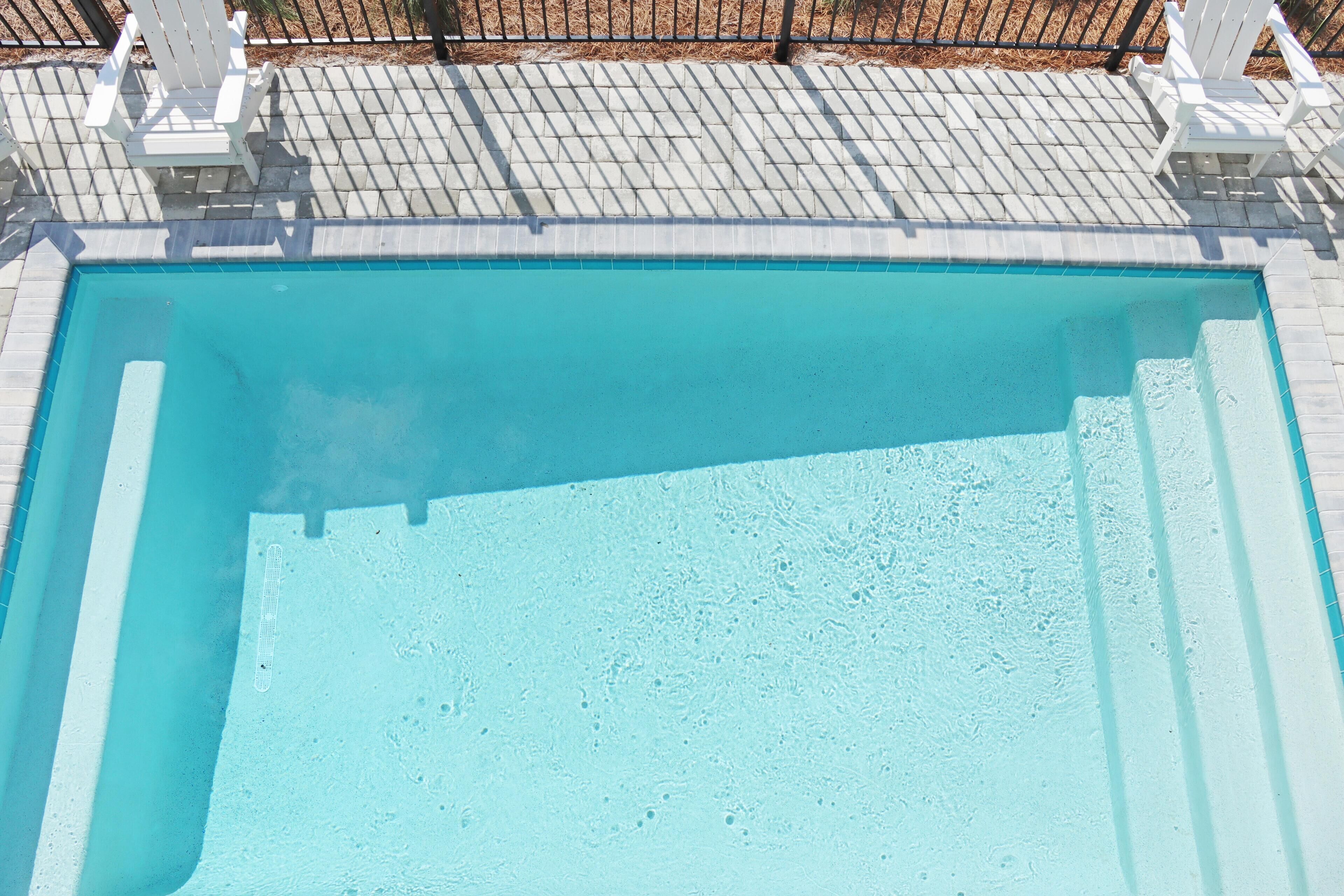 Une piscine rectangulaire entourée d’une terrasse carrelée.