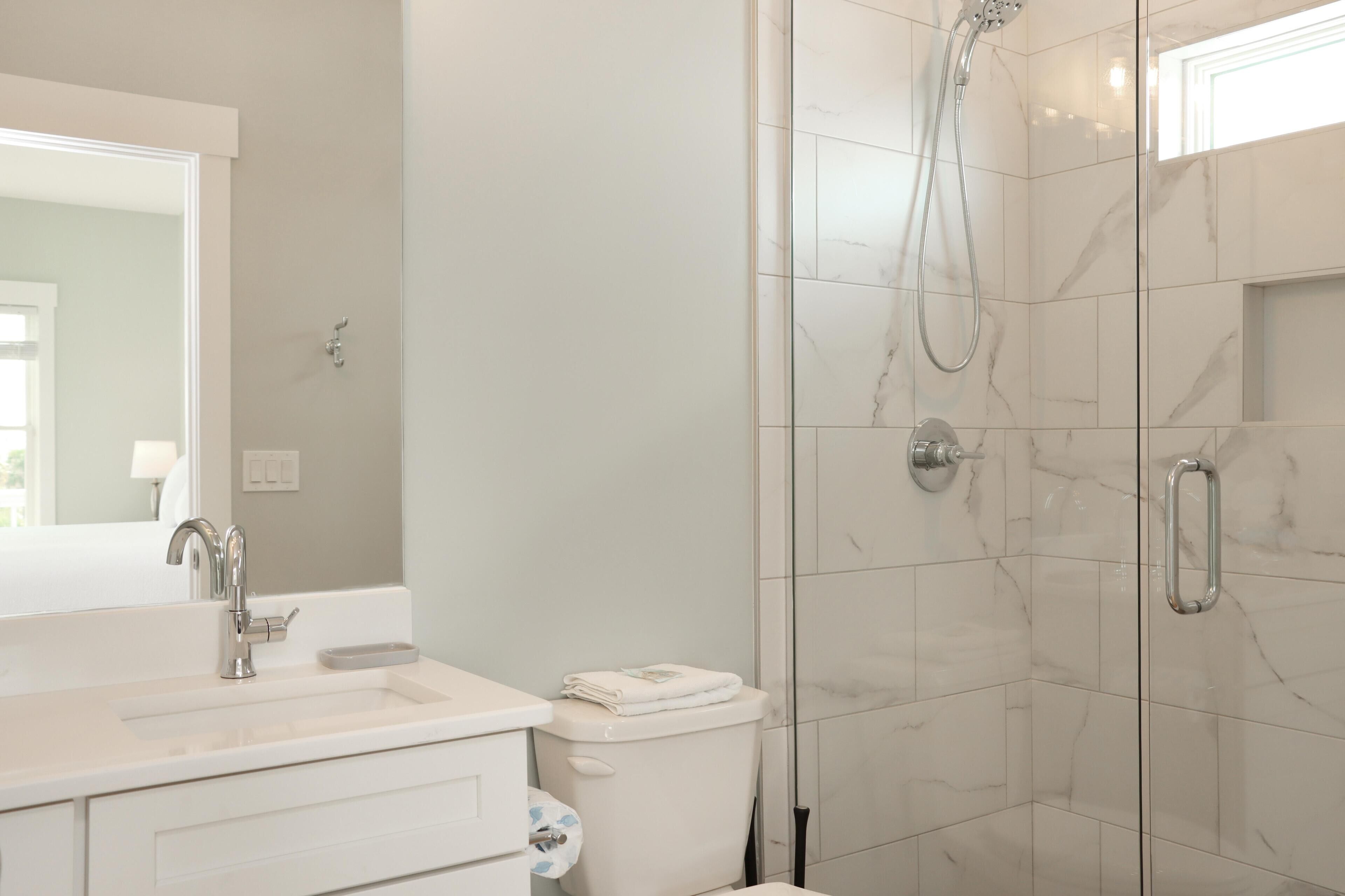 A modern bathroom with a white sink, mirror, and toilet.