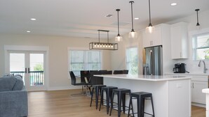 Una cocina moderna con una isla central, taburetes de bar e iluminación colgante.
