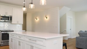 Una cocina moderna con armarios blancos, electrodomésticos de acero inoxidable e iluminación colgante.