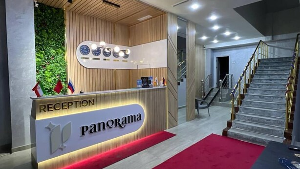 A reception area with a wooden reception desk, a red carpet, and a staircase. - Hotel Panorama Samarkand (Samarkand)