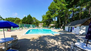 A swimming pool with lounge chairs and umbrellas, surrounded by trees and a small building. - Dog-Friendly 3BR Townhome with All Seasons Room – Bayberry Woods (Bethany Beach)