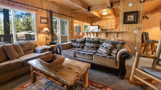 L’intérieur chaleureux d’un chalet, avec un décor en bois, un canapé, une table basse et un fauteuil à bascule.