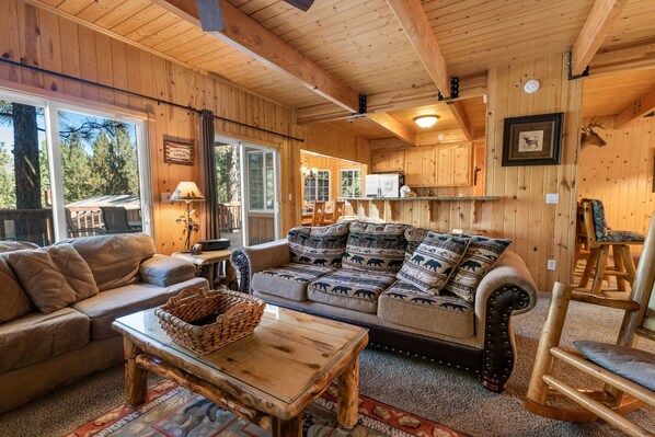 L’intérieur chaleureux d’un chalet, avec un décor en bois, un canapé, une table basse et un fauteuil à bascule.
