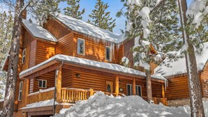 Une cabane en bois dotée d’un balcon, entourée d’arbres couverts de neige.