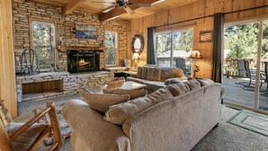 Un intérieur de chalet chaleureux avec une cheminée en pierre, un plafond en bois et un grand canapé.