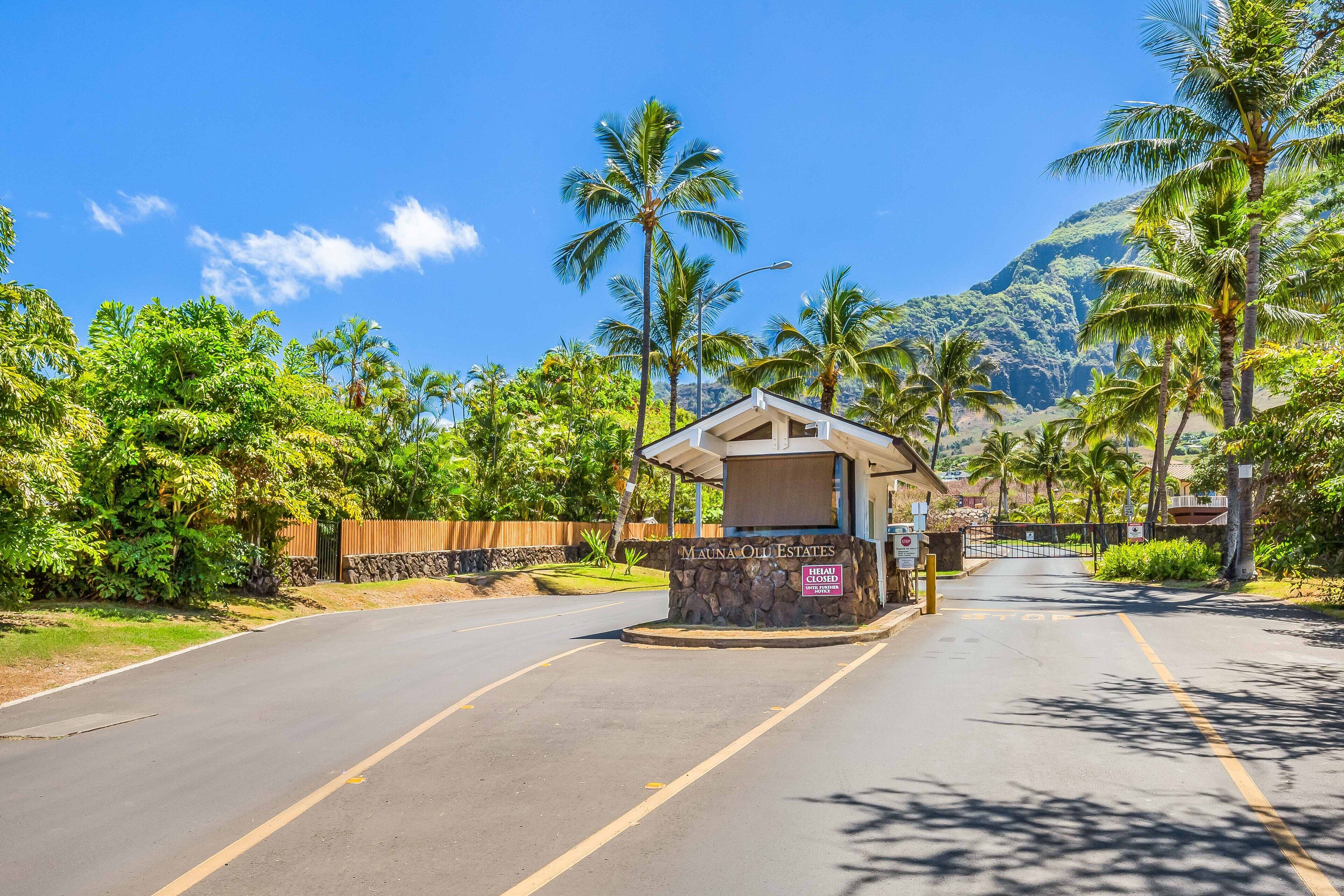 A road leading to a gated entrance with a sign reading "Mauna Old Estates."