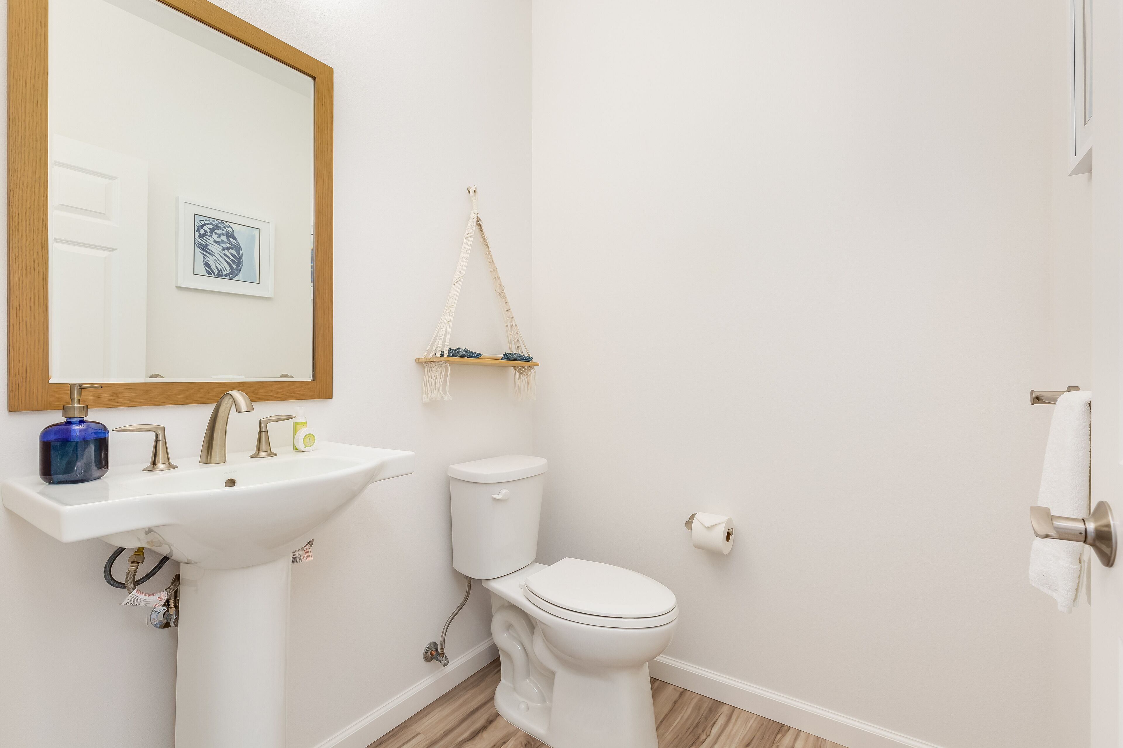 A bathroom with a white sink, a toilet, a mirror, and a towel rack.