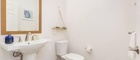 A bathroom with a white sink, a toilet, a mirror, and a towel rack.