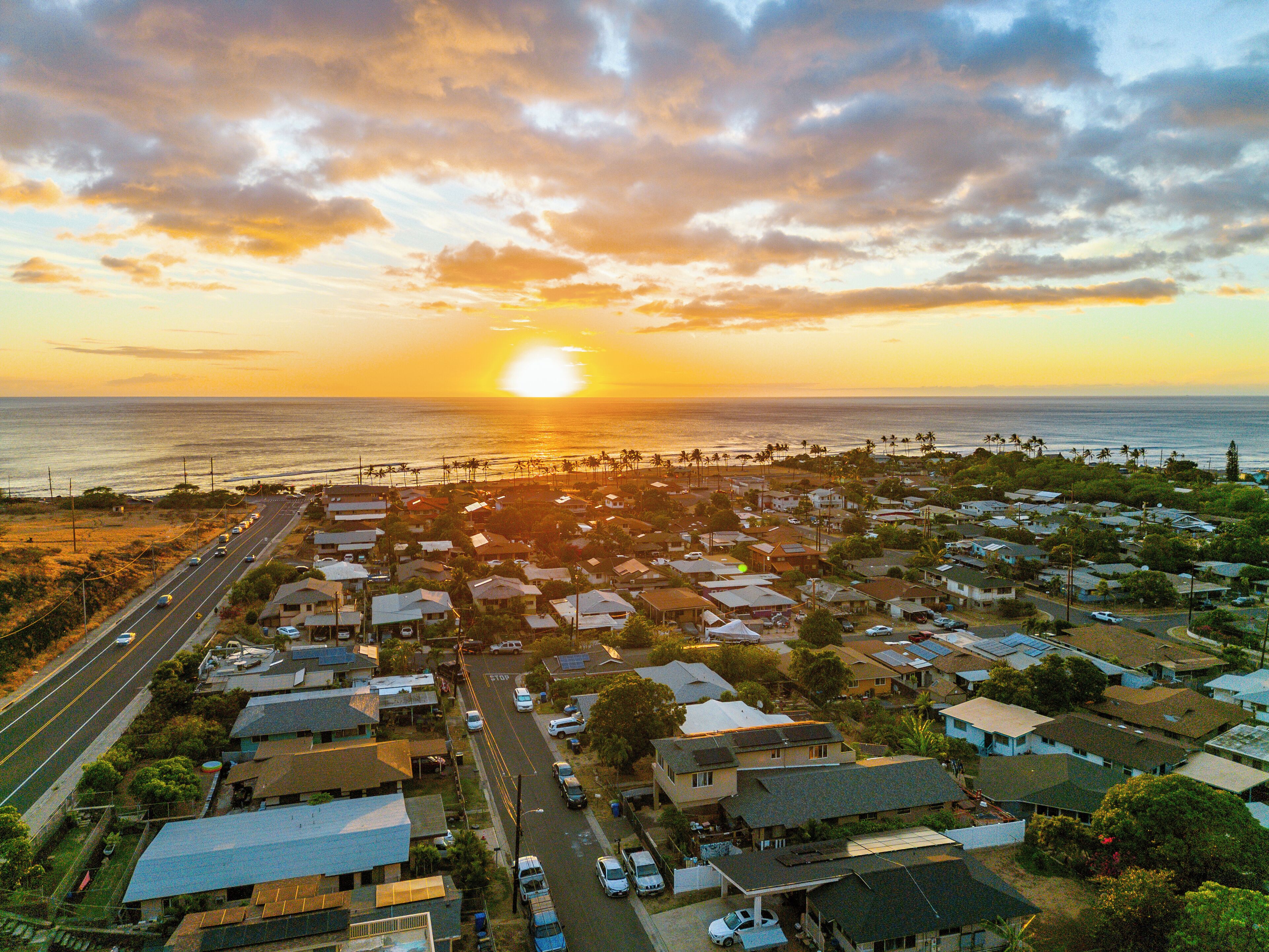 A coastal residential area with houses, a road, and a beach.