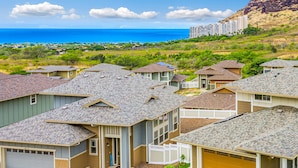 Zona residencial con casas de techos inclinados, un césped bien cuidado y vistas al océano.