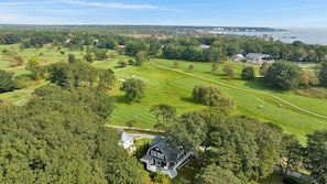 A large estate with a golf course, a prominent house, and a coastal view.