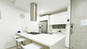 A modern kitchen with a central island, stainless steel appliances, and white cabinetry. - Exclusive 3 Bedrooms - Samaria Beach Club (Santa Marta)