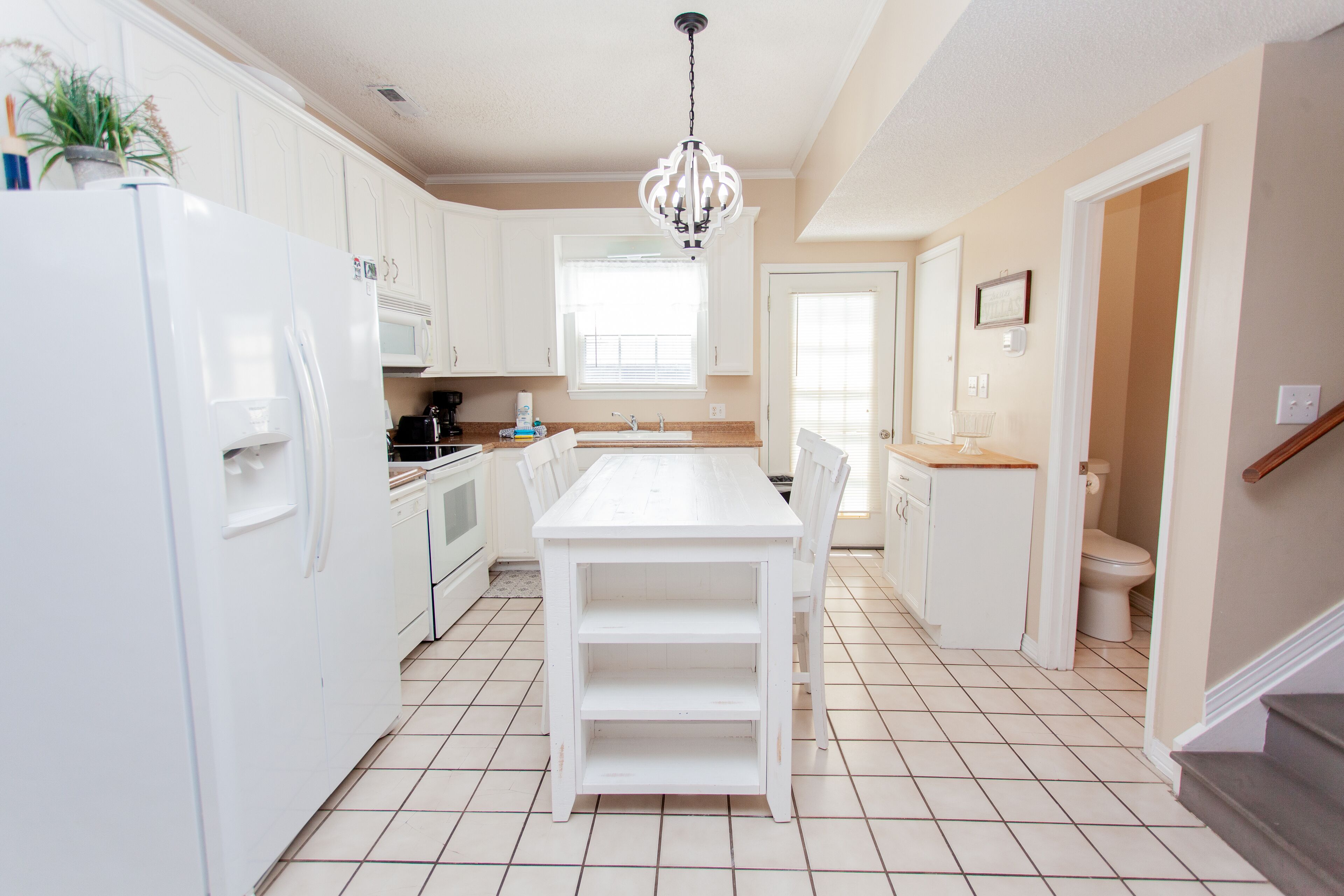 A kitchen with white cabinets, a white dining table, and a central island.