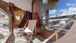 Una terraza de madera con una silla, una mesa y vistas a una montaña nevada.