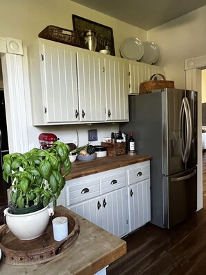 Une cuisine avec des armoires blanches, un réfrigérateur en acier inoxydable et un comptoir en bois.