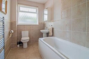 A bathroom with a toilet, sink, and bathtub. - Pear Tree House - Stylish Home in Nottingham. (Beeston)