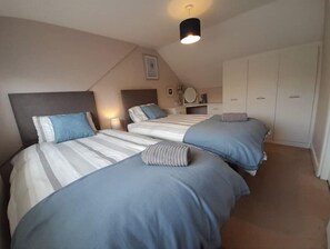 A bedroom with two beds, a ceiling light, a clock, and a wardrobe. - Pear Tree House - Stylish Home in Nottingham. (Beeston)